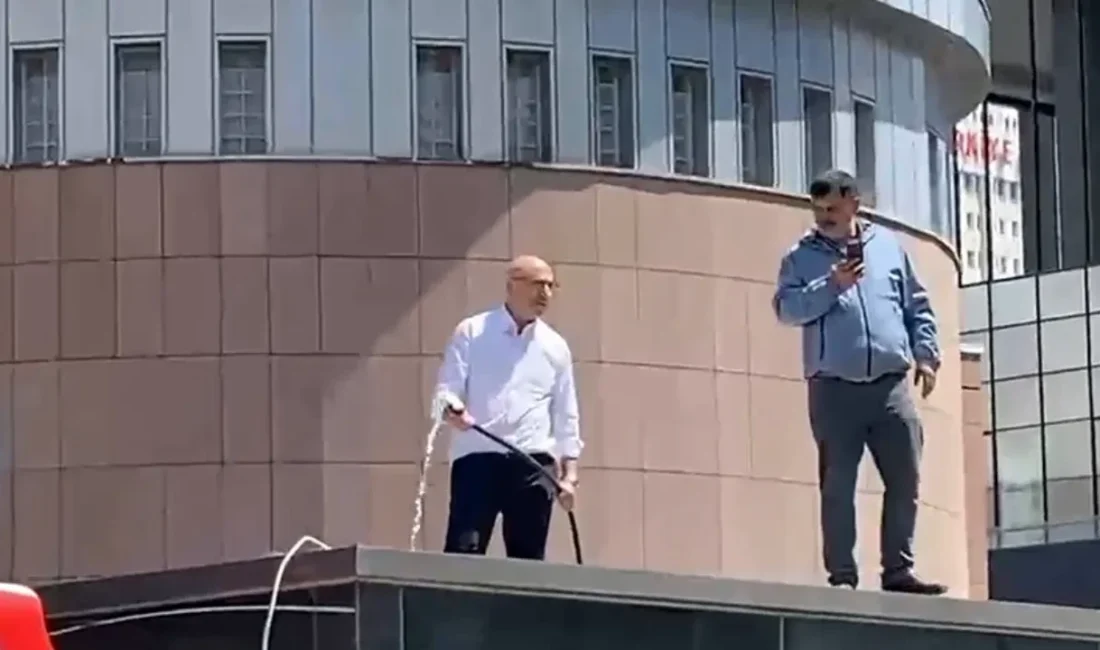 Mahmut Tanal, su hortumuyla parti binasının önündeki güvenlik kulübesinin üstüne