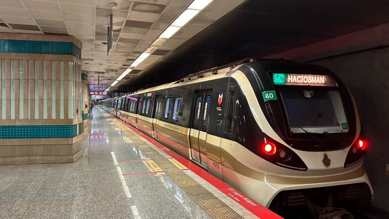 Metro train on an underground platform labeled M2 Haciosman, approaching with red tail lights visible on the front.